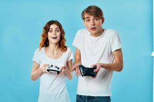 jovem casal camiseta com joysticks dentro mãos vídeo jogos tecnologia azul fundo foto