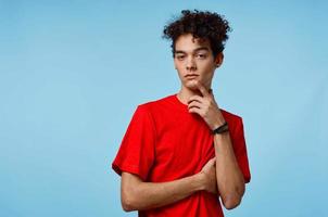 alegre cara com encaracolado cabelo dentro uma vermelho camiseta gestos com dele mãos foto