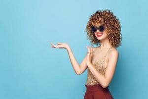 senhora sorrir encaracolado cabelo vermelho lábios gesto com mãos cópia de espaço vermelho calça foto