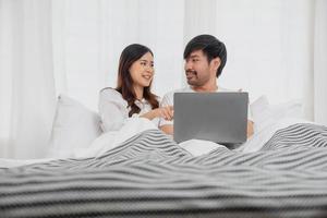 jovem feliz ásia casal usando computador portátil dentro cama assistindo filme, romântico Tempo para realçar família relação, família conceito. foto