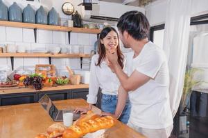 jovem ásia casal cozinhando com frutas e legumes e usando computador portátil dentro a cozinha para cozinhar Comida juntos dentro a família Felizmente, família conceito. foto