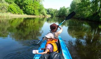 família caiaque viagem. mãe e filha remo uma barco em a rio, uma água caminhada, uma verão aventura. ecológico e extremo turismo, ativo e saudável estilo de vida foto