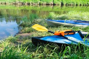 canoas turísticas com remos ficam na costa do rio no verão em uma caminhada na água. rafting em barcos infláveis e caiaques duplos e triplos, viagem em família, aventura extrema no verão foto