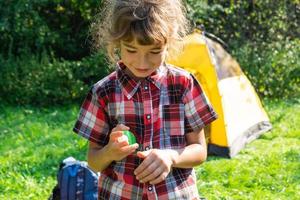 menina pulveriza spray de mosquito na pele na natureza que morde as mãos e os pés. proteção contra picadas de insetos, repelente seguro para crianças. recreação ao ar livre, contra alergias. horário de verão foto