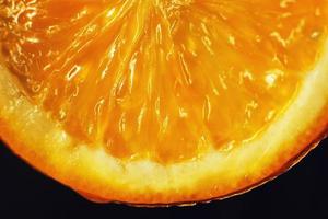 laranja fatia macro com uma solta do água fundo . suculento laranja fatiado fechar-se em uma Sombrio fundo foto