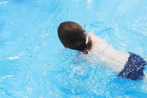 Garoto nada dentro a piscina. Garoto Aprendendo para nadar dentro a piscina foto