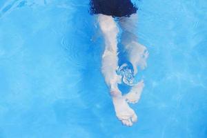 Garoto nada dentro a piscina. Garoto Aprendendo para nadar. pés dentro a piscina fechar foto