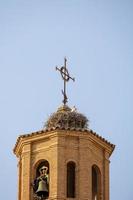 cegonha ninho em a Igreja torre contra uma azul céu com pássaros foto