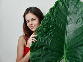 bonita mulher dentro vermelho roupa de banho verde Palma folha isolado fundo sorrir foto