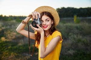 mulher fotógrafo segurando uma Câmera perto face Veja a parte, de lado sorrir natureza foto