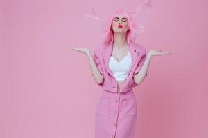 beleza moda mulher dentro uma Rosa terno gesticulando com dele mãos emoções Diversão Rosa fundo inalterado foto