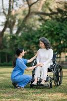 idosos ásia Senior mulher em cadeira de rodas com ásia Cuidado cuidador. enfermagem casa hospital jardim conceito. dentro Sol luz foto