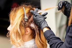 cabeleireiro aplicando corante para vertente do cabelo foto