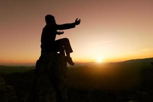 homem rezando ao pôr do sol montanhas levantou as mãos viajar estilo de vida espiritual relaxamento conceito emocional, liberdade e aventura de viagem. foto