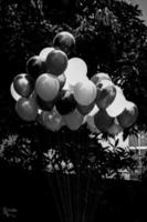 uma grupo do colorida cheio de gás balões em Sombrio fundo. Preto e branco imagem. foto