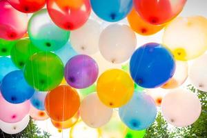luz solar contra colorida cheio de gás balões em anexo para a fio. colorida balões fundo. foto