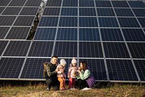 família com dois filhas em a fundo do solar painéis. eco energia. foto