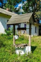 poço velho com balde de ferro na cadeia longa forjada para água potável foto