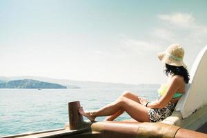 turista viajante mulher viagem desfrutando passeio em Alto fim Rapidez barco em verão período de férias. elegante Preto bikini, grandes cabelo e Sol bronzeada corpo. Omã meio leste feriado destino foto