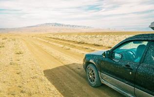 carro fica na estrada de cascalho em área deserta no parque nacional de vashlovani. viagem extrema no cáucaso foto