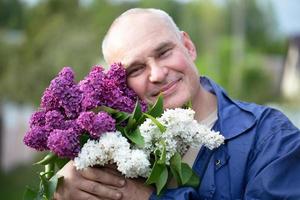 idosos homem com uma ramalhete do flores brutal grisalho homem com uma lindo lilás. foto