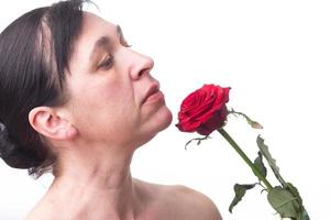 face do uma maduro mulher com uma rosa. sinais do pele envelhecimento depois de 40. foto