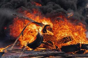 queimando carros rodas, Forte chama do Laranja vermelha fogo e Preto nuvens dentro céu foto