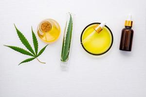 garrafa de vidro de óleo de cannabis e folhas de cânhamo montada em fundo branco foto