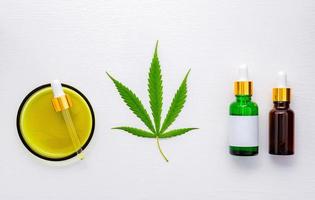 garrafa de vidro de óleo de cannabis e folhas de cânhamo montada em fundo branco foto