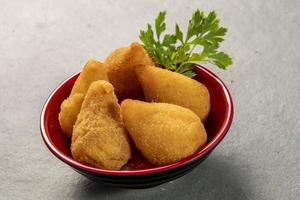 tradicional frito coxinha dentro prato em ardósia fundo, popular brasileiro lanche foto