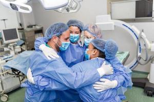 parcial Visão do trabalha duro masculino e fêmea hospital equipe dentro cheio protetora vestem em pé juntos dentro grupo abraço foto