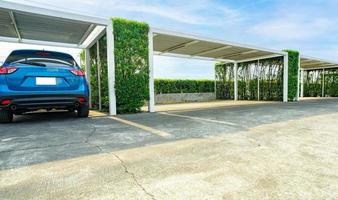 carro estacionamento muitos com esvaziar espaço. estacionamento zona em ensolarado verão dia e esvaziar espaço. visão traseira do azul suv carro estacionado às ao ar livre carro estacionamento muitos com verde cerca cerca. ecológico ao ar livre estacionamento muito. foto