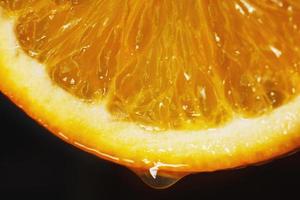 laranja fatia com uma solta do água fechar acima em uma Preto fundo foto