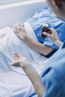 lado Visão do diverso médicos examinando ásia fêmea paciente dentro cama dentro enfermaria às hospital. foto