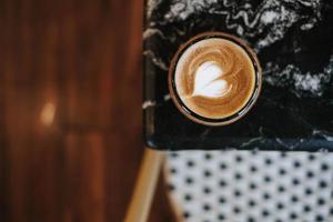 uma copo do café com café com leite arte em Preto mármore mesa foto