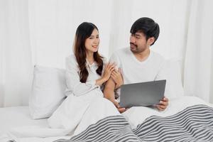 jovem feliz ásia casal usando computador portátil dentro cama assistindo filme, romântico Tempo para realçar família relação, família conceito. foto