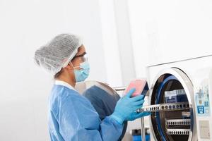 jovem fêmea cientista esterilizando laboratório material dentro autoclave foto