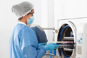 jovem fêmea cientista esterilizando laboratório material dentro autoclave foto