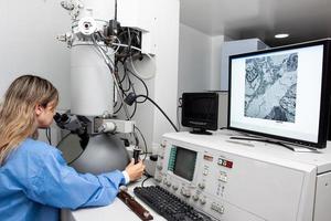 jovem fêmea cientista trabalhando às a laboratório com a elétron microscópio foto