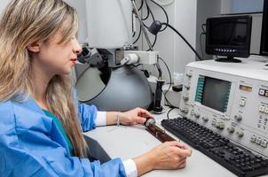 jovem fêmea cientista Carregando uma rede com a espécime em a amostra suporte do uma transmissão elétron microscópio foto