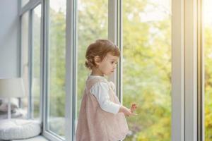 pequeno menina em pé em janela peitoril foto