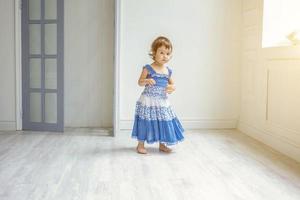 pequeno menina dançando dentro brilhante luz vivo quarto às casa e rindo foto