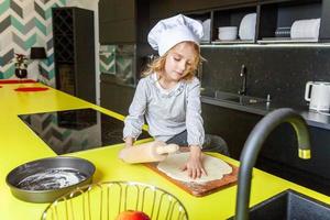 pequeno menina preparando massa, assar caseiro feriado maçã torta dentro cozinha foto