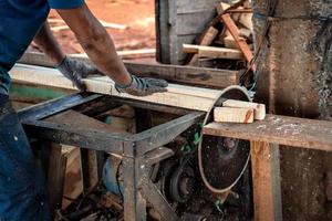 fechar-se do uma trabalhador mãos corte madeira com uma circular Serra dentro uma serraria. foto
