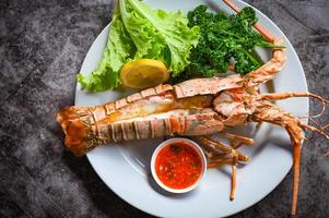 espinhoso lagosta Comida em placa, fresco lagosta ou Rocha lagosta frutos do mar com erva e especiarias limão coentro salsinha alface salada, lagosta para cozinhando Comida e frutos do mar molho foto