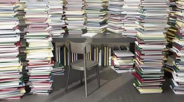 mesa cercada por muitos livros empilhados ao redor