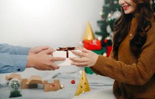 presente de natal nas mãos. homem feliz dando caixa de presente de natal e ano novo para mulher em casa. celebração de natal em família. Decoração de Natal. foto