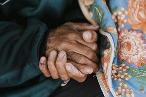 morador de rua segurando suas mãos com cobertor foto