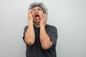 retrato do uma furioso Senior grisalho homem gritando e gritando e gesticulando dentro medo com mãos e face em isolado fundo foto
