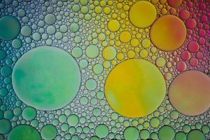 círculos de óleo multicoloridos na água, fundo colorido foto